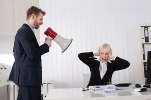 Boss Shouting At Young Businesswoman Through Loudspeaker In Office